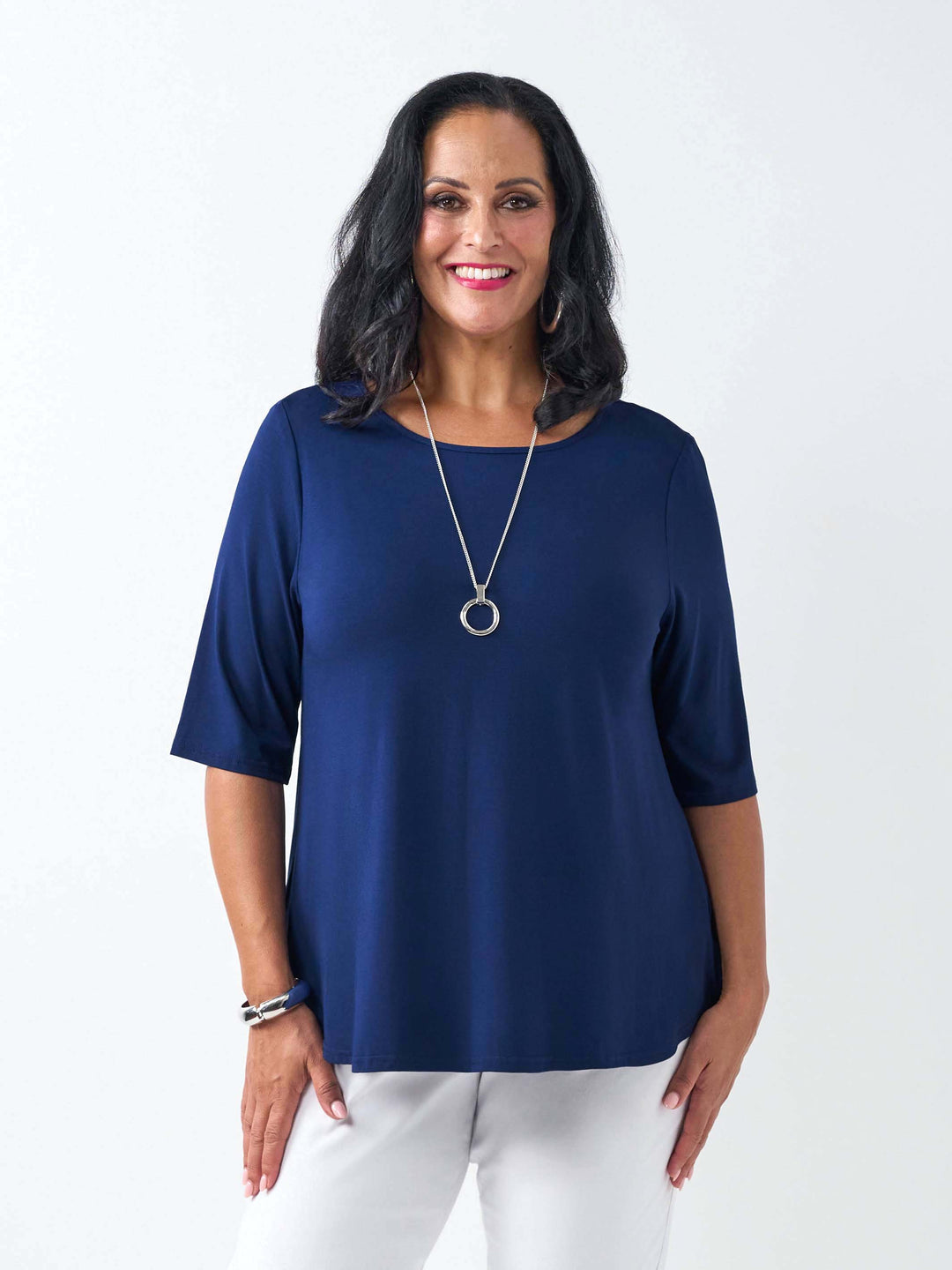 A woman modeling a navy blue three-quarter sleeve top and white pants