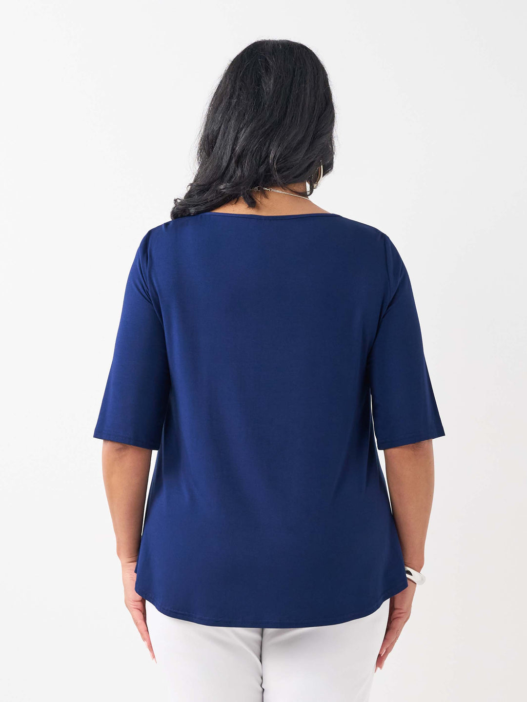 A woman viewed from the back wearing a navy blue short-sleeve top and white pants