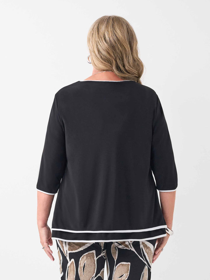 a woman viewed from back wearing a plain black v-neck swing layered top with contrast white trim