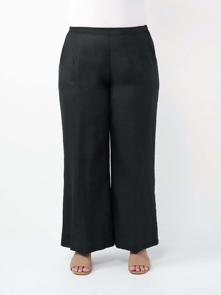Black wide-leg linen pants shown on a model from the waist down