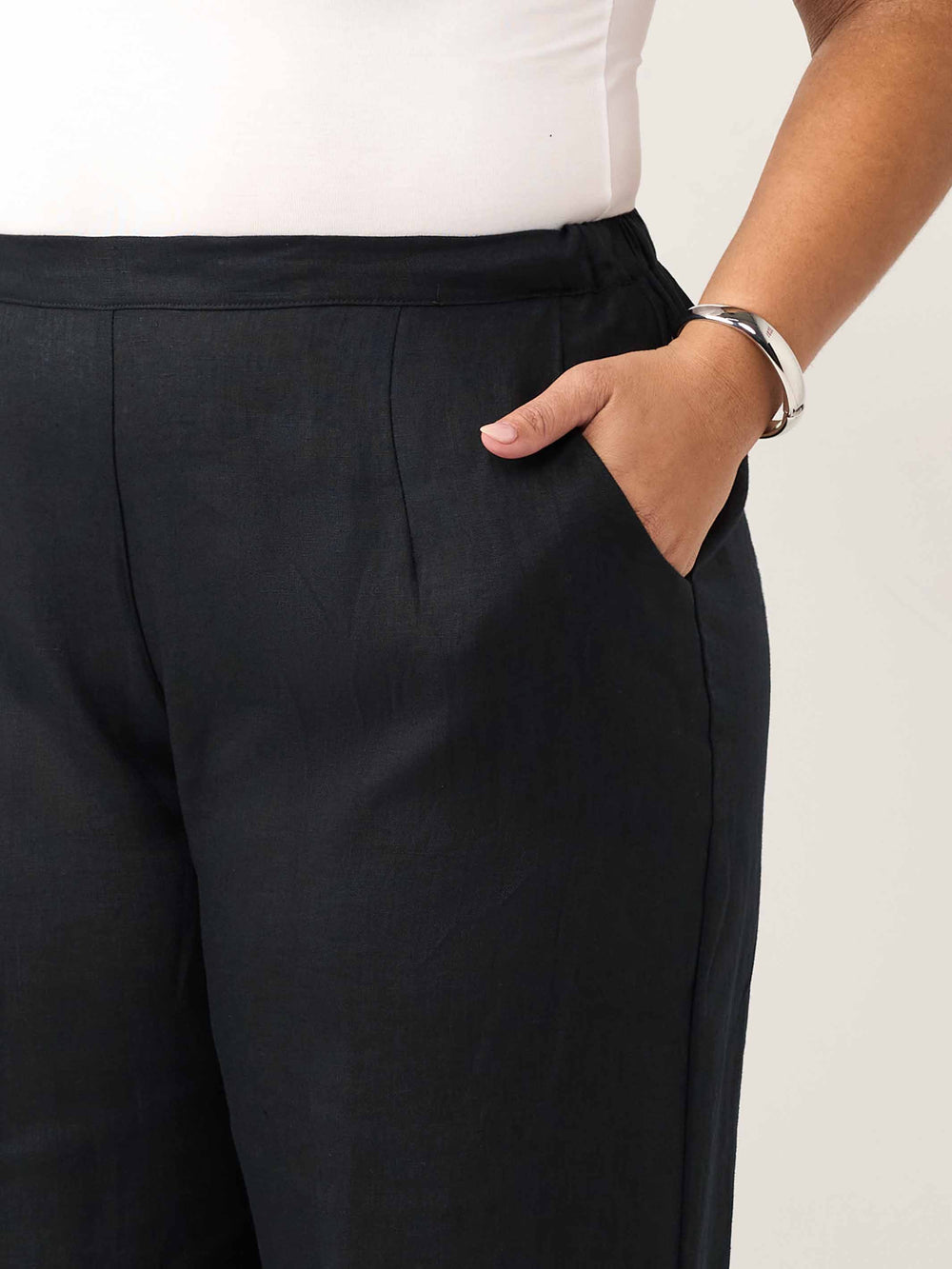 Close-up of a person wearing black wide-leg trousers with a side pocket