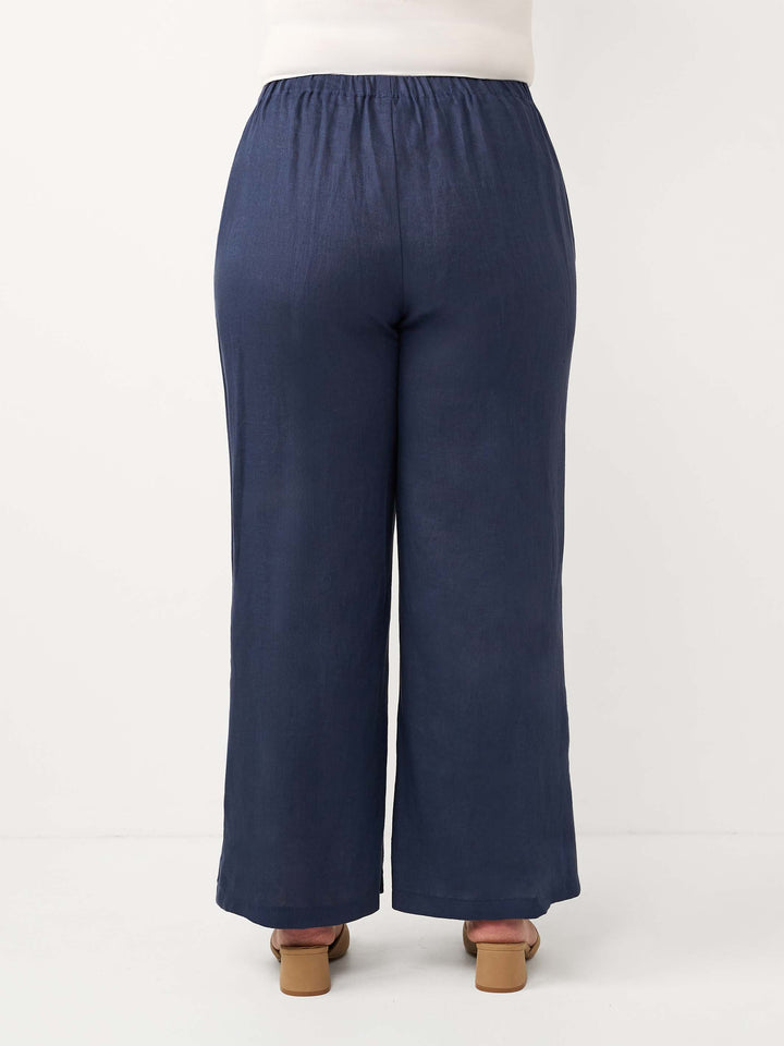 A woman shown from the back wearing wide-leg navy linen pants with an elastic waistband