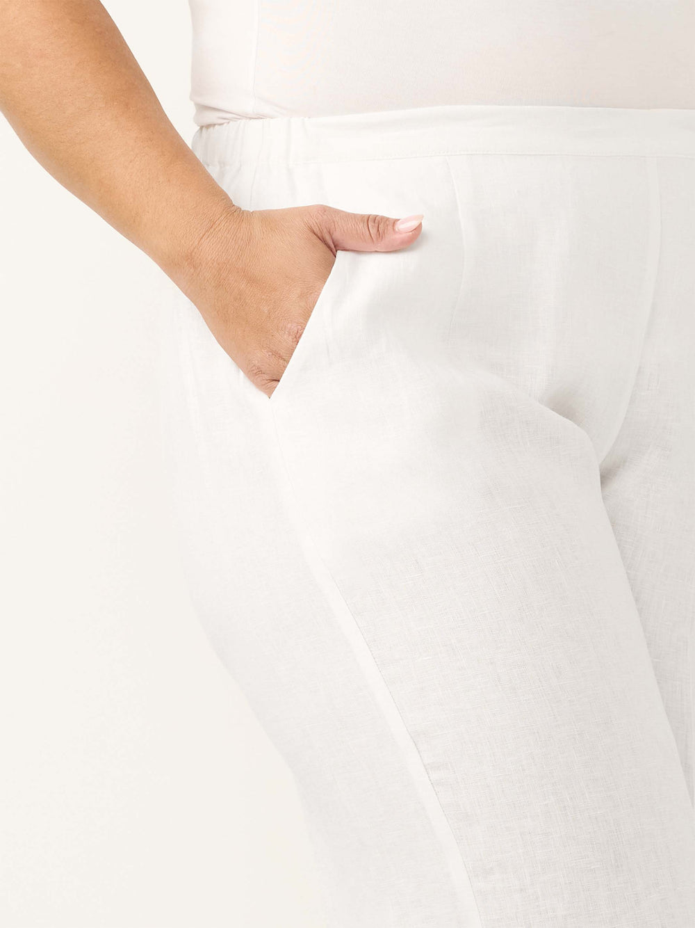 Close-up of a woman wearing white linen pants, showing the side pocket
