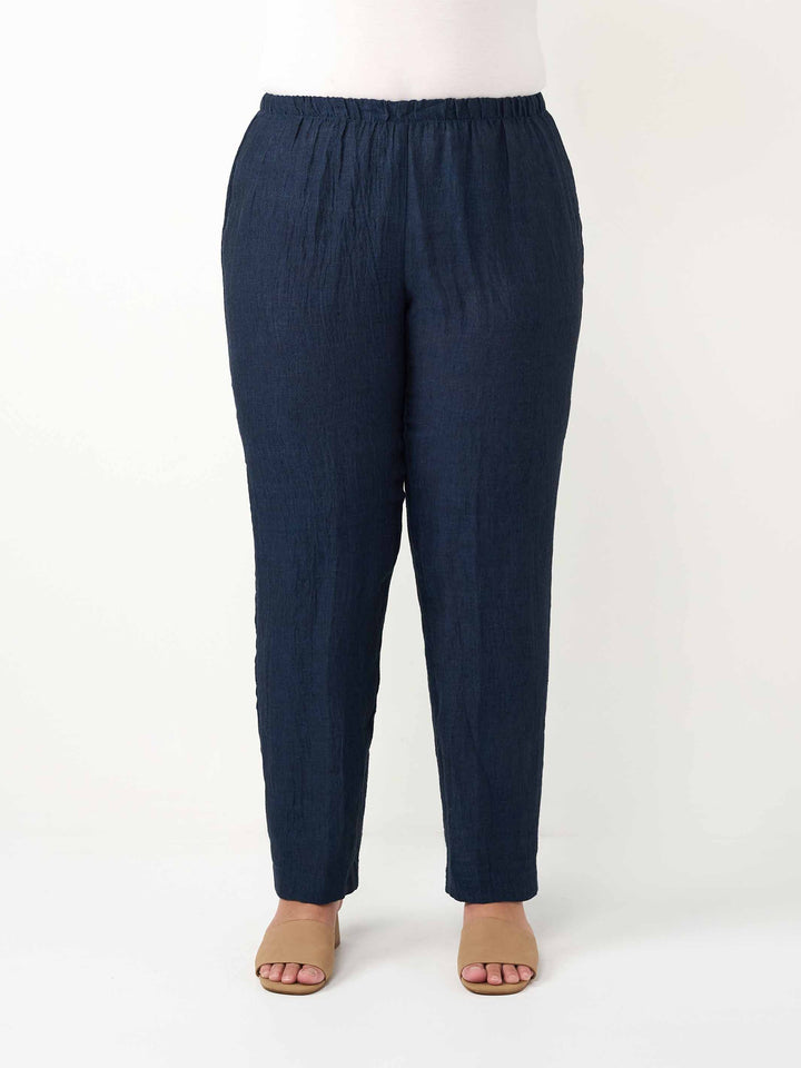 A person modeling dark navy blue relaxed-fit pants with an elastic waistband 
