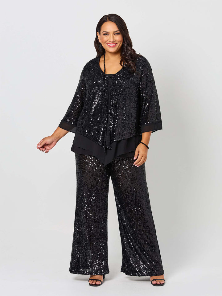 A woman wearing a black sequined three-quarter sleeve evening jacket with layered ruffle hem, paired with matching sequined pants