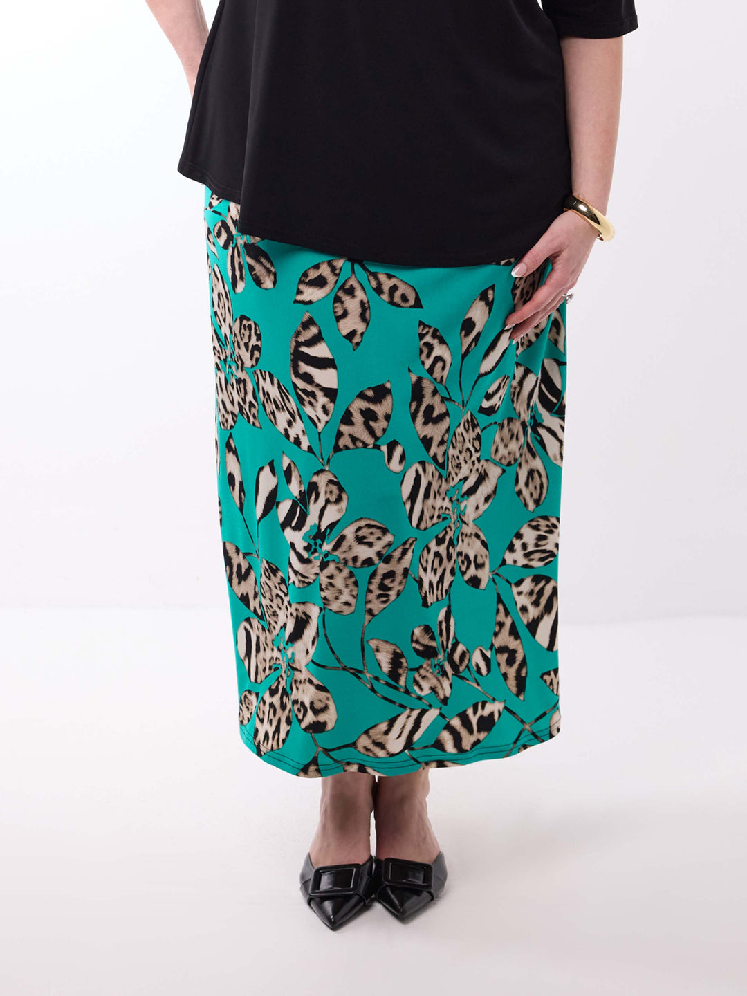 A model wearing a teal green midi skirt with a leopard print pattern, styled with a black top 