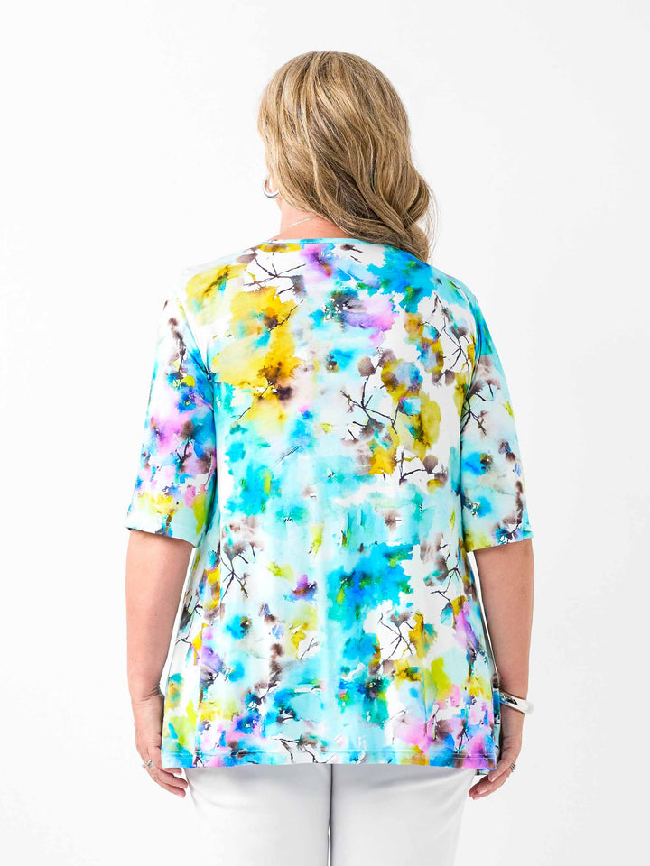 A back view of a woman wearing a short-sleeve jersey top with a vibrant blue watercolour floral print
