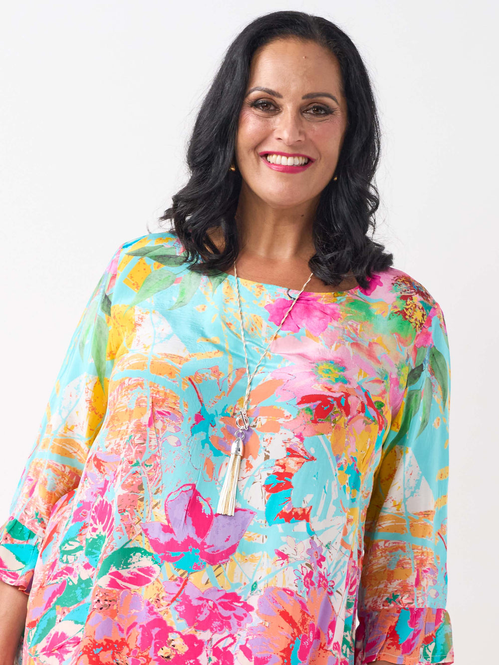 A woman wearing a vibrant floral printed top with three-quarter length frill cuff.