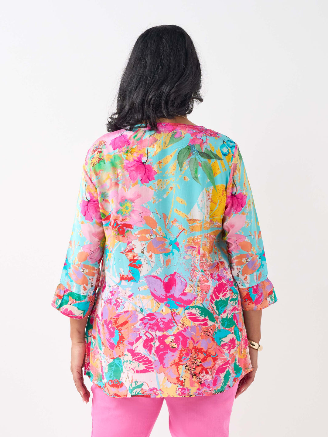 A woman wearing a vibrant floral printed top with three-quarter length frill cuff.
