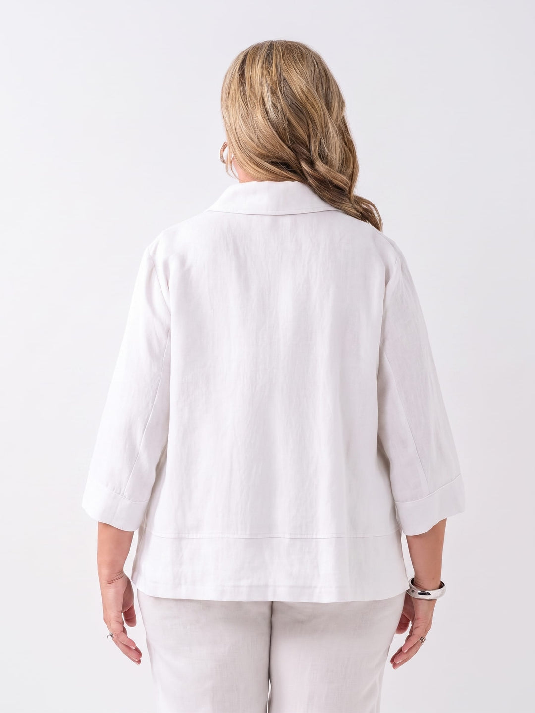 A woman viewed from the back wearing a white linen three-quarter sleeve jacket 