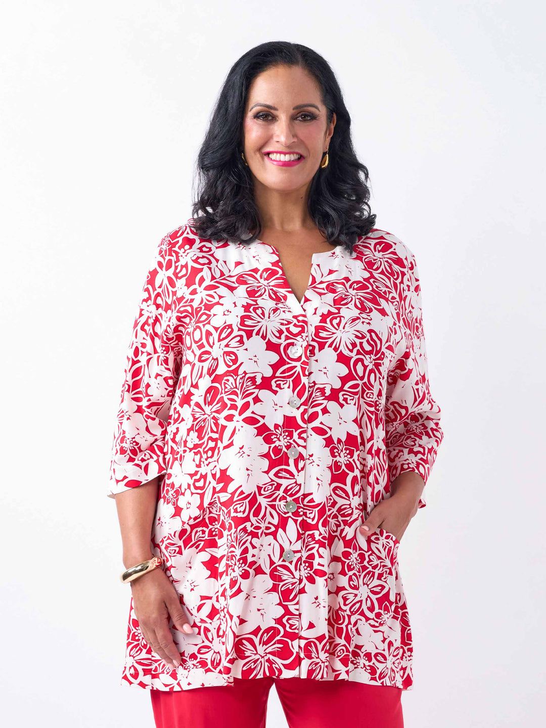 A woman wearing a red and white floral print tunic top with three-quarter sleeves, paired with red pants