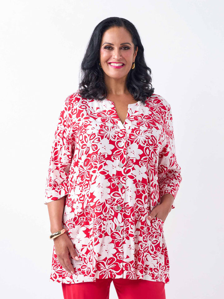 A woman wearing a red and white floral print tunic top with three-quarter sleeves, paired with red pants