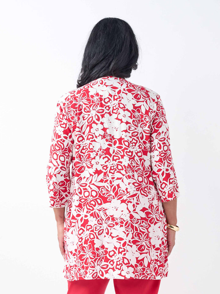 A back view of a woman wearing a red and white floral print tunic top with three-quarter sleeves, paired with red pants