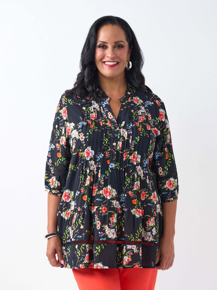 A woman wearing a black floral three-quarter-sleeve button-up top with lace detail