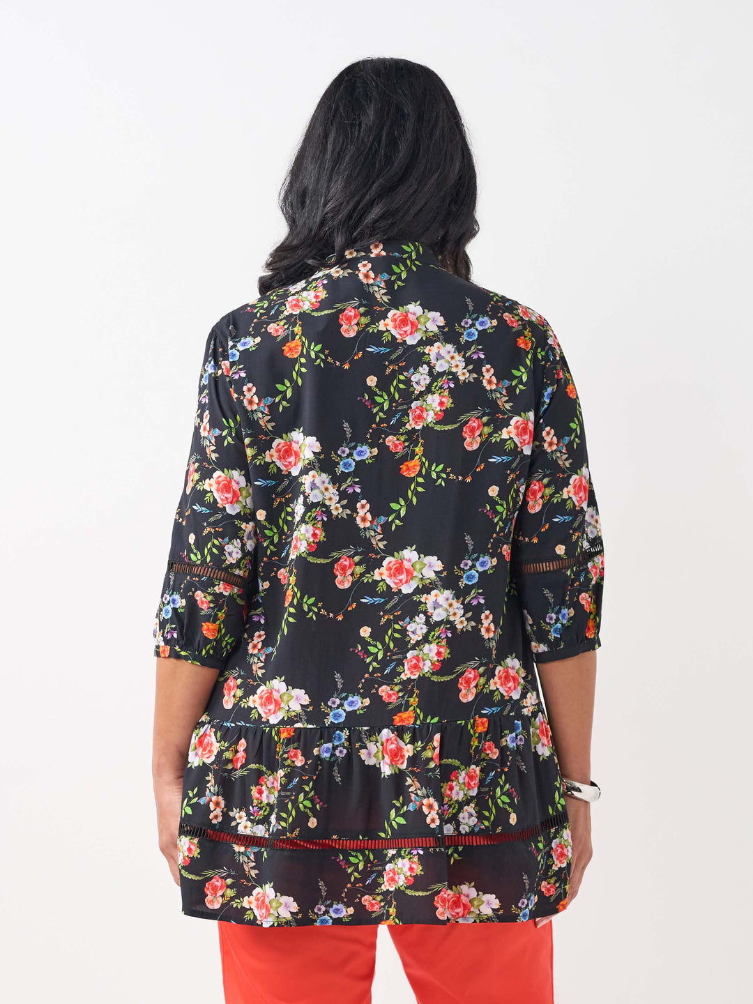 A woman wearing a black floral three-quarter-sleeve button-up top with lace detail