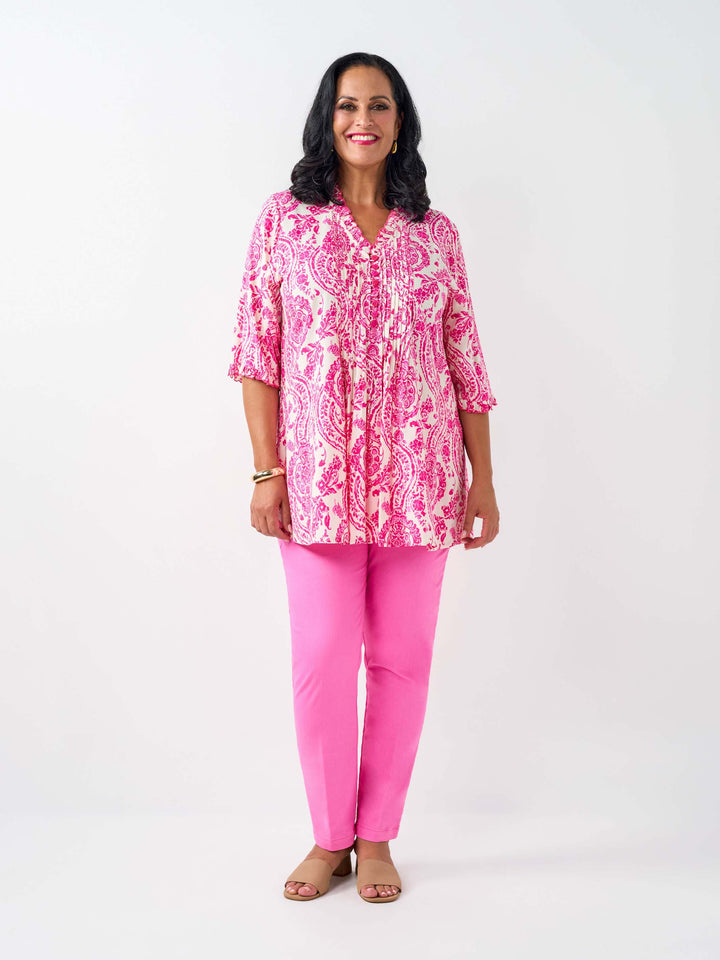A woman wearing a pink and white paisley print tunic top with pinktucked front and three-quarter ruffled sleeves, paired with pink pants