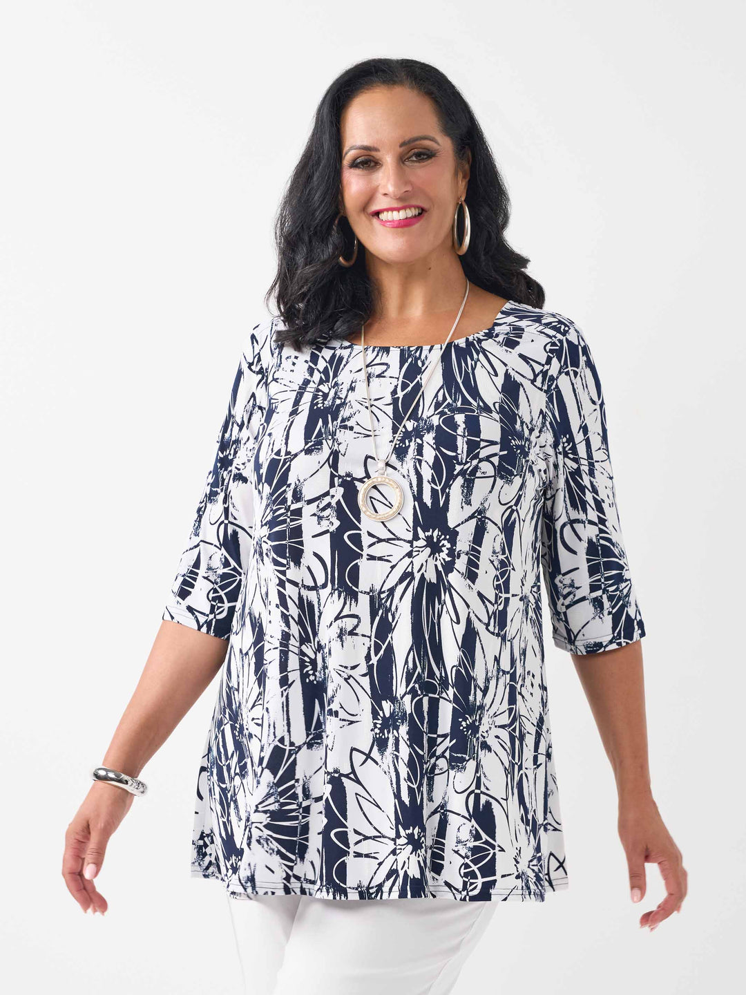 front view of model wearing a navy and white abstract floral print short-sleeve top paired with white pants 