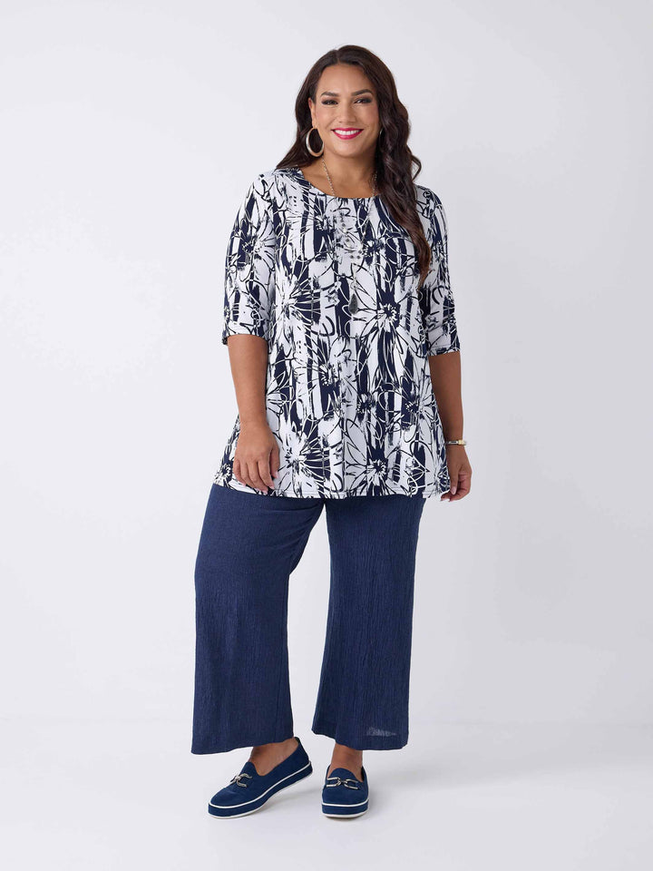model wearing a navy and white abstract floral print short-sleeve top paired with dark navy blue linen pants 