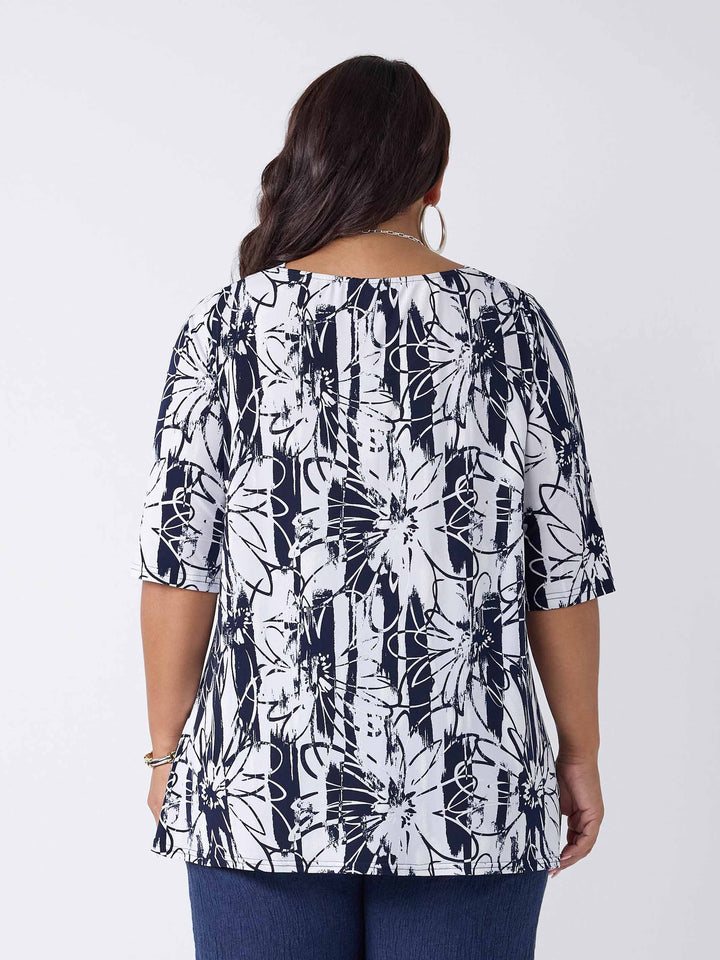 back view of model wearing a navy and white abstract floral print short-sleeve top paired with dark navy blue linen pants 