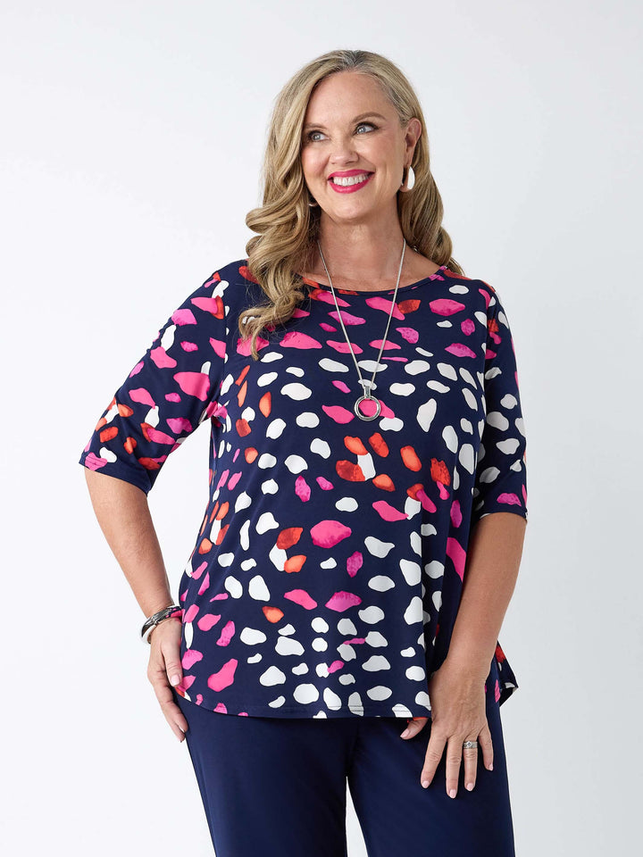 front view of model wearing navy blue short-sleeve top with a coloruful pebbles print in pink and white, paired with navy jersey pants