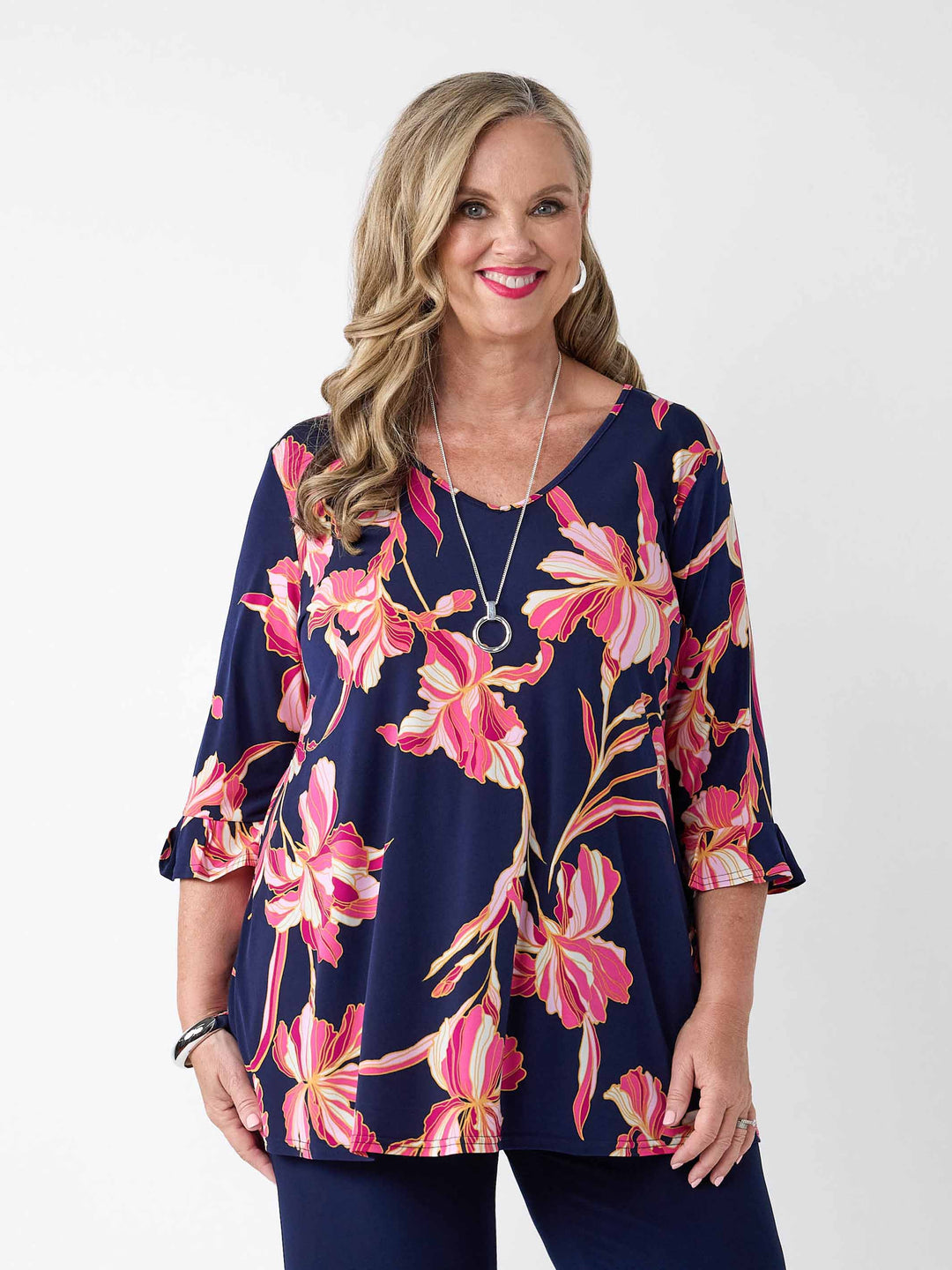 A woman wearing a navy blue V-neck top with a pink floral print, paired with navy pants
