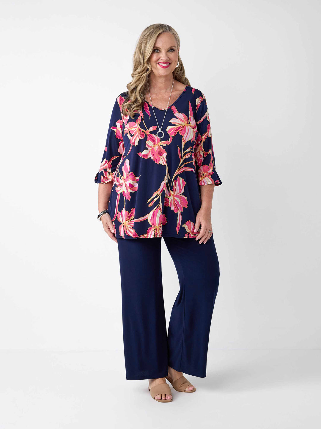 A woman wearing a navy blue top with a floral print top with three-quarter ruffled sleeves, paired with navy palazzo wide-leg pant