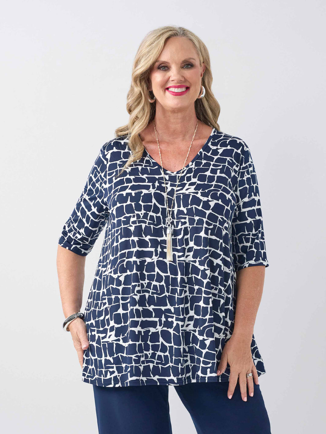 front view of model wearing a navy blue and white abstract patterned v-neck swing jersey top with three-quarter sleeves