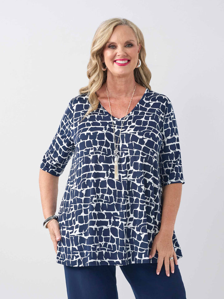 front view of model wearing a navy blue and white abstract patterned v-neck swing jersey top with three-quarter sleeves