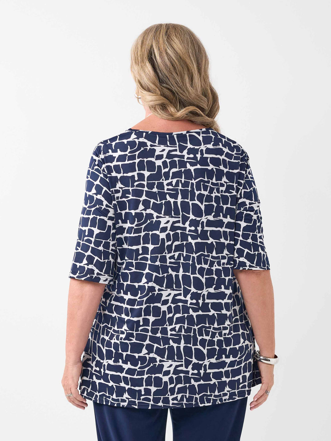 back view of model wearing a navy blue and white abstract patterned v-neck swing jersey top with three-quarter sleeves