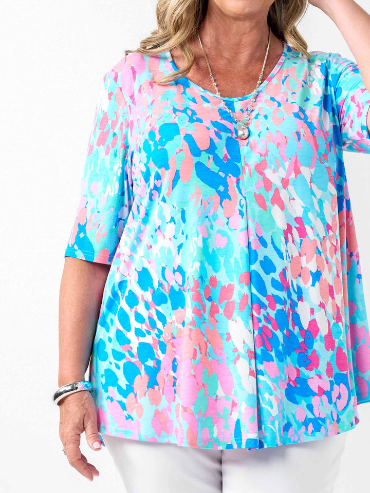 a woman wearing a fresh aqua blue and pink print top with elbow length sleeves and invert pleat