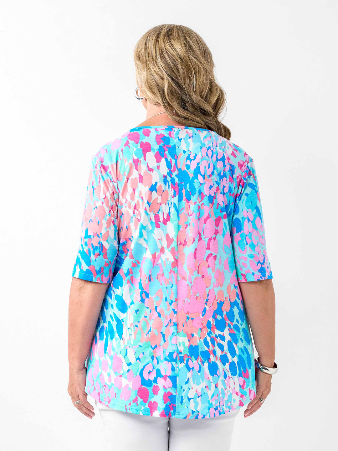 a woman wearing a fresh aqua blue and pink print top with elbow length sleeves and invert pleat