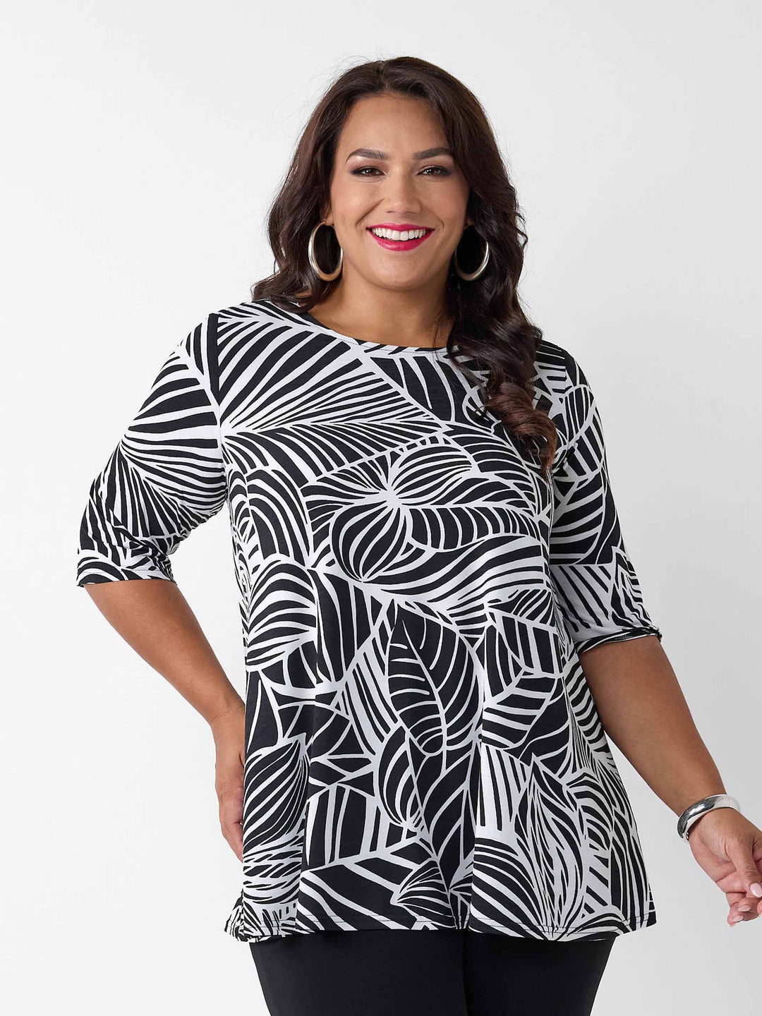 front view of model wearing a black and white tropical leaf print three-quarter length sleeve top paired with black palazzo jersey pant