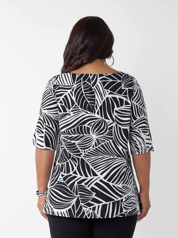 back view of model wearing a black and white tropical leaf print three-quarter length sleeve top paired with black palazzo jersey pant