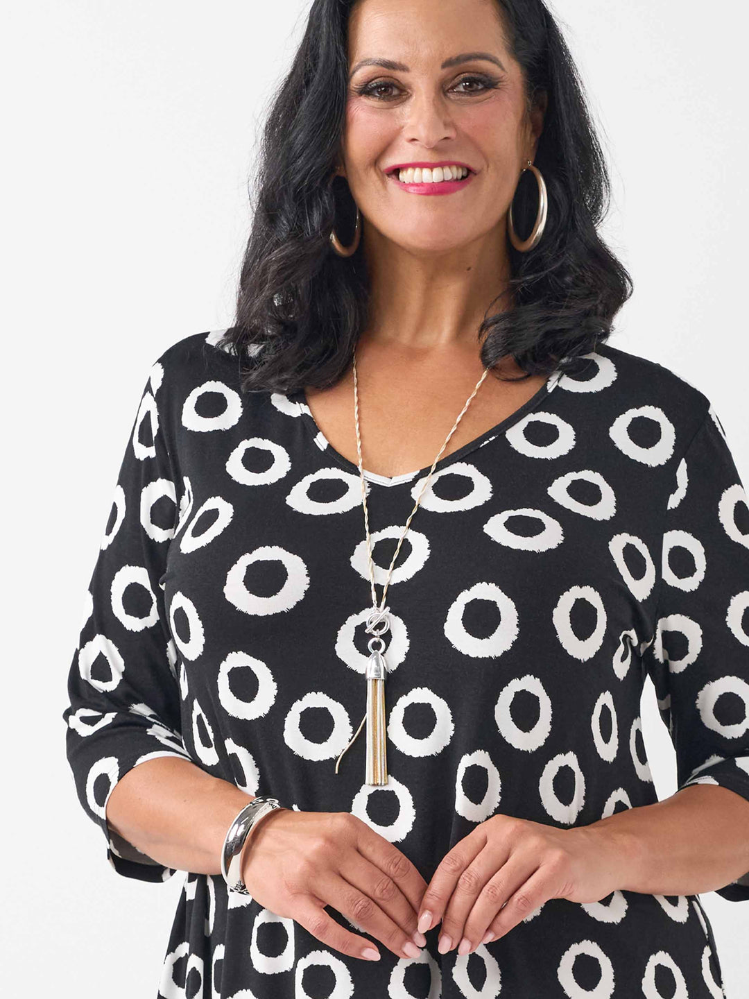 A woman wearing a black three-quarter sleeve top with a white circular dot pattern