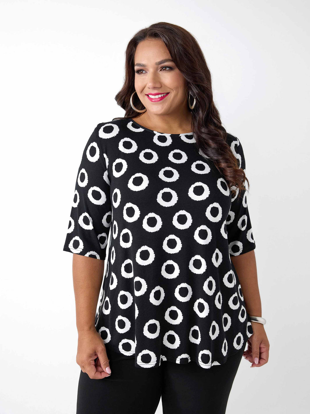A woman wearing a black short-sleeve top with a white circular dot pattern, paired with black pants
