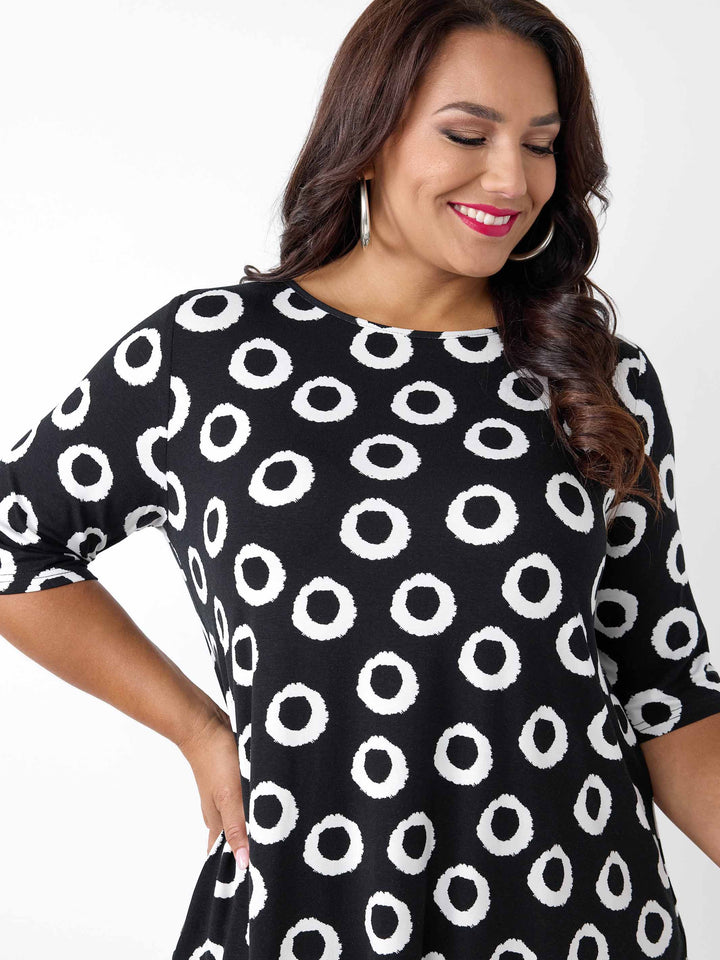 A woman wearing a black short-sleeve top with a white circular dot pattern