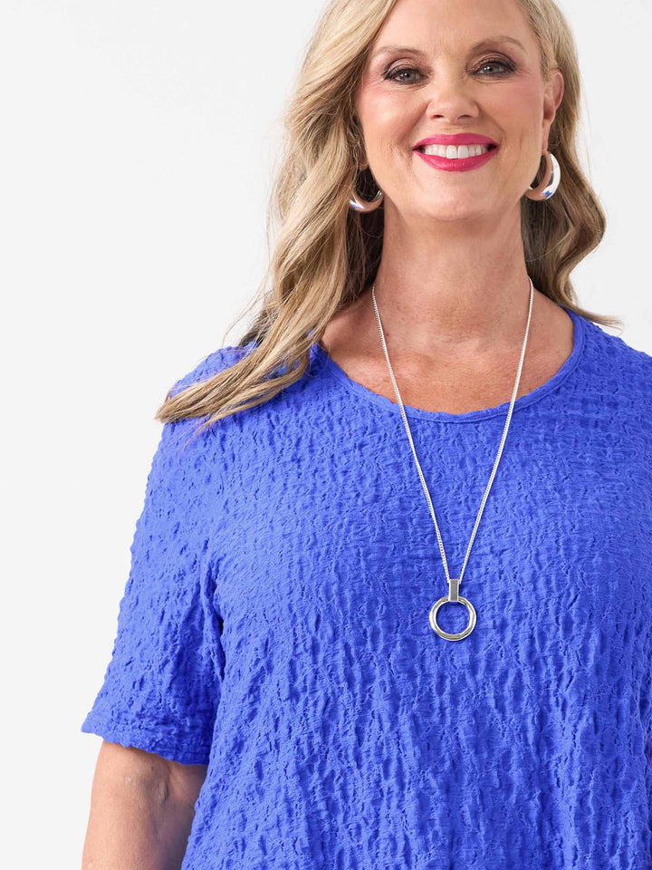 A woman wearing a bright blue textured short-sleeve top
