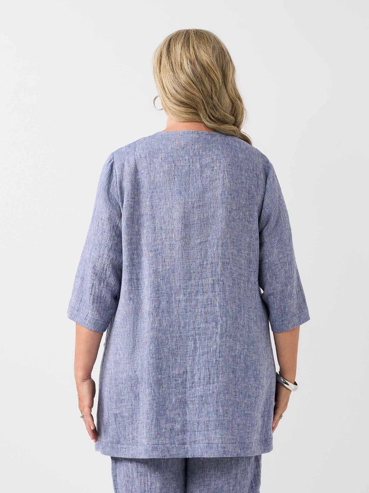 back view of model wearing a plain navy blue textured crinkle linen button-front top with matching pants