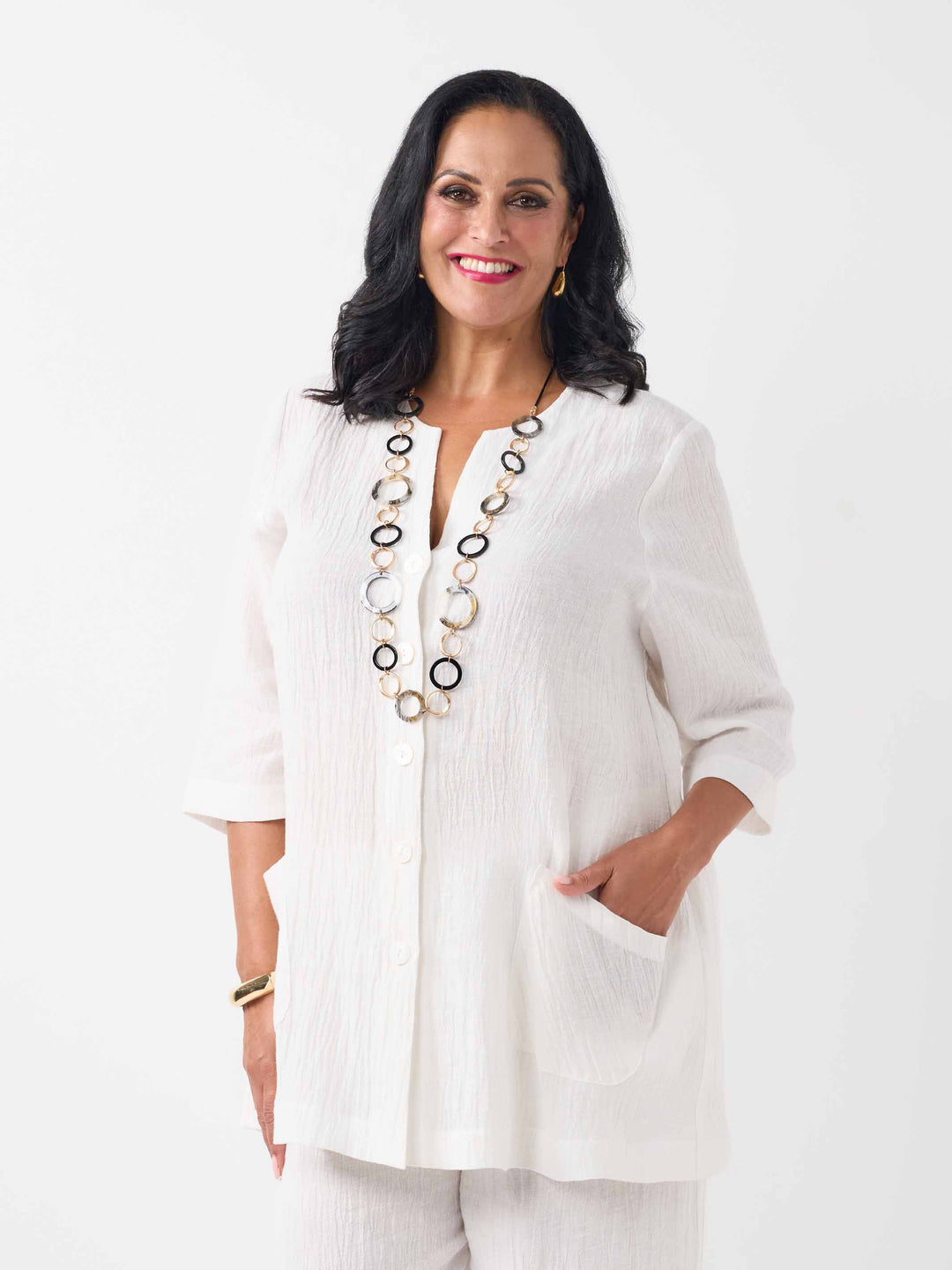 front view of model wearing a white textured crinkle linen button-up top with two front pockets