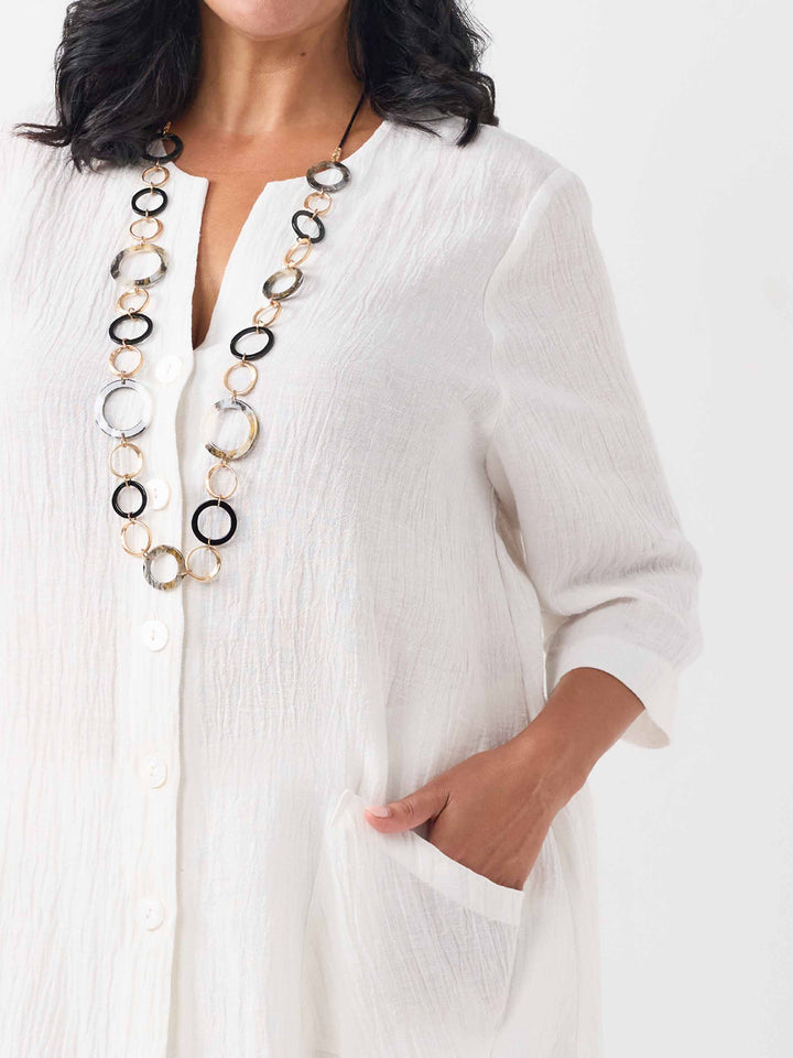 close-up view of model wearing a white textured crinkle linen button-up top with front pockets