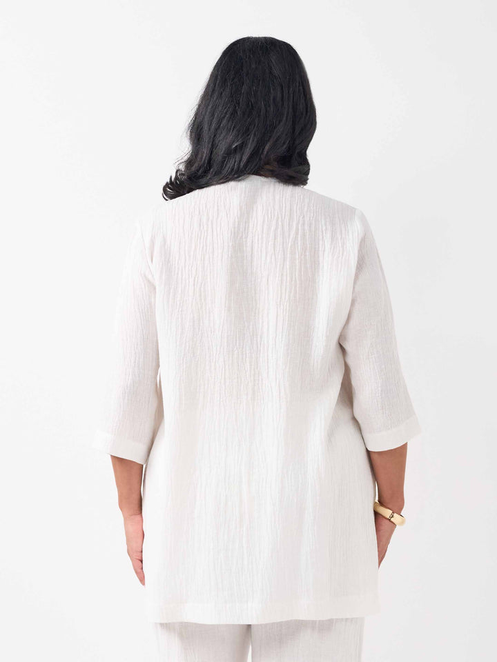 back view of model wearing a white textured crinkle linen button-up top