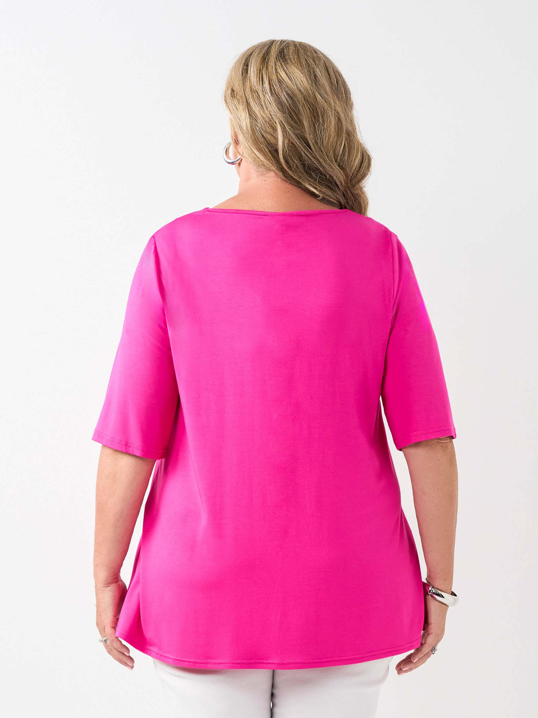 A woman viewed from the back wearing a bright pink short-sleeve top and white pants