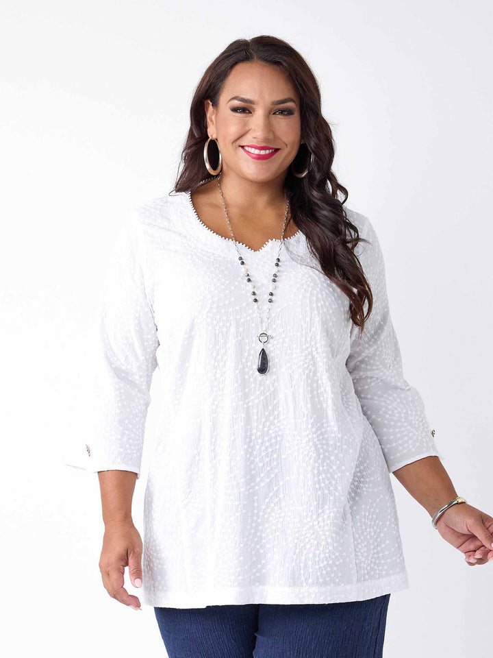 model wearing a white three-quarter sleeves top with a textured, dotted pattern
