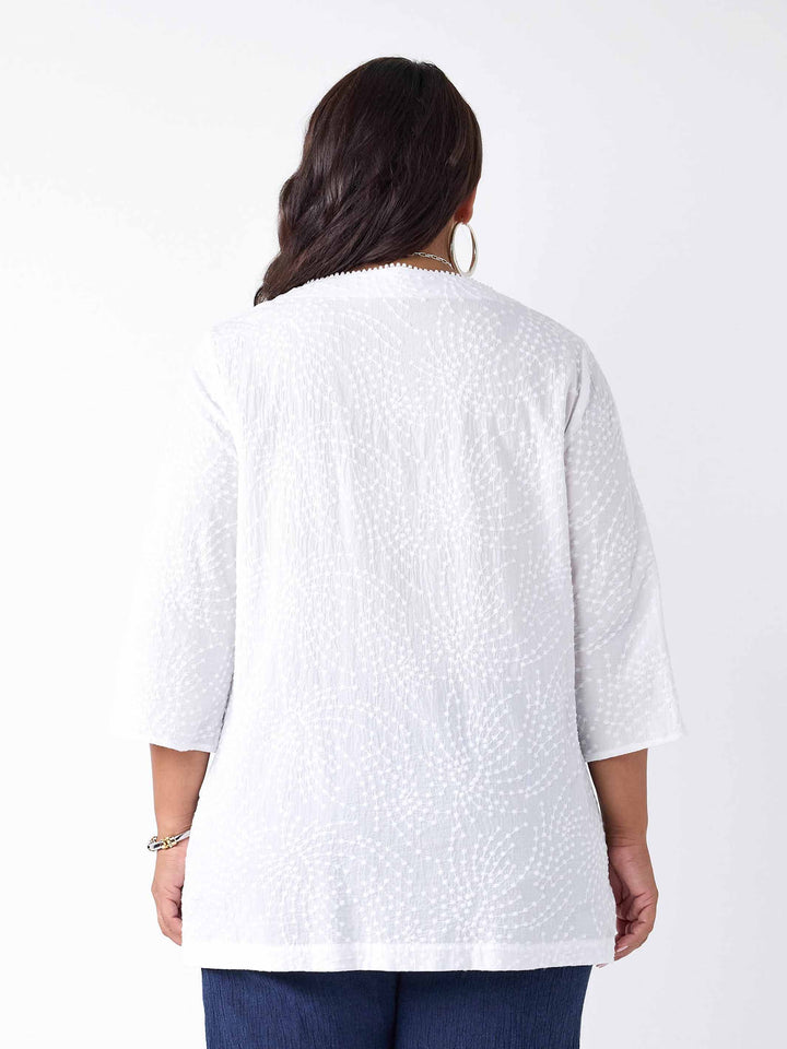 back view of model wearing a white three-quarter sleeves top with a textured, dotted pattern