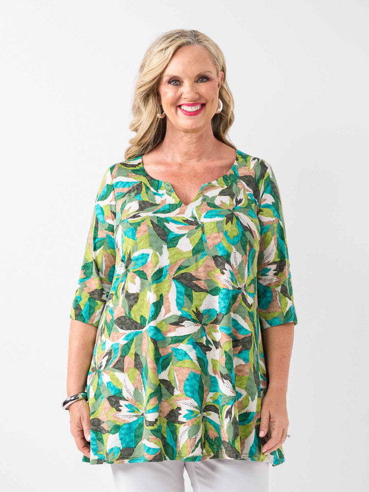 A woman wearing a green tropical floral print tunic top with three-quarter sleeves