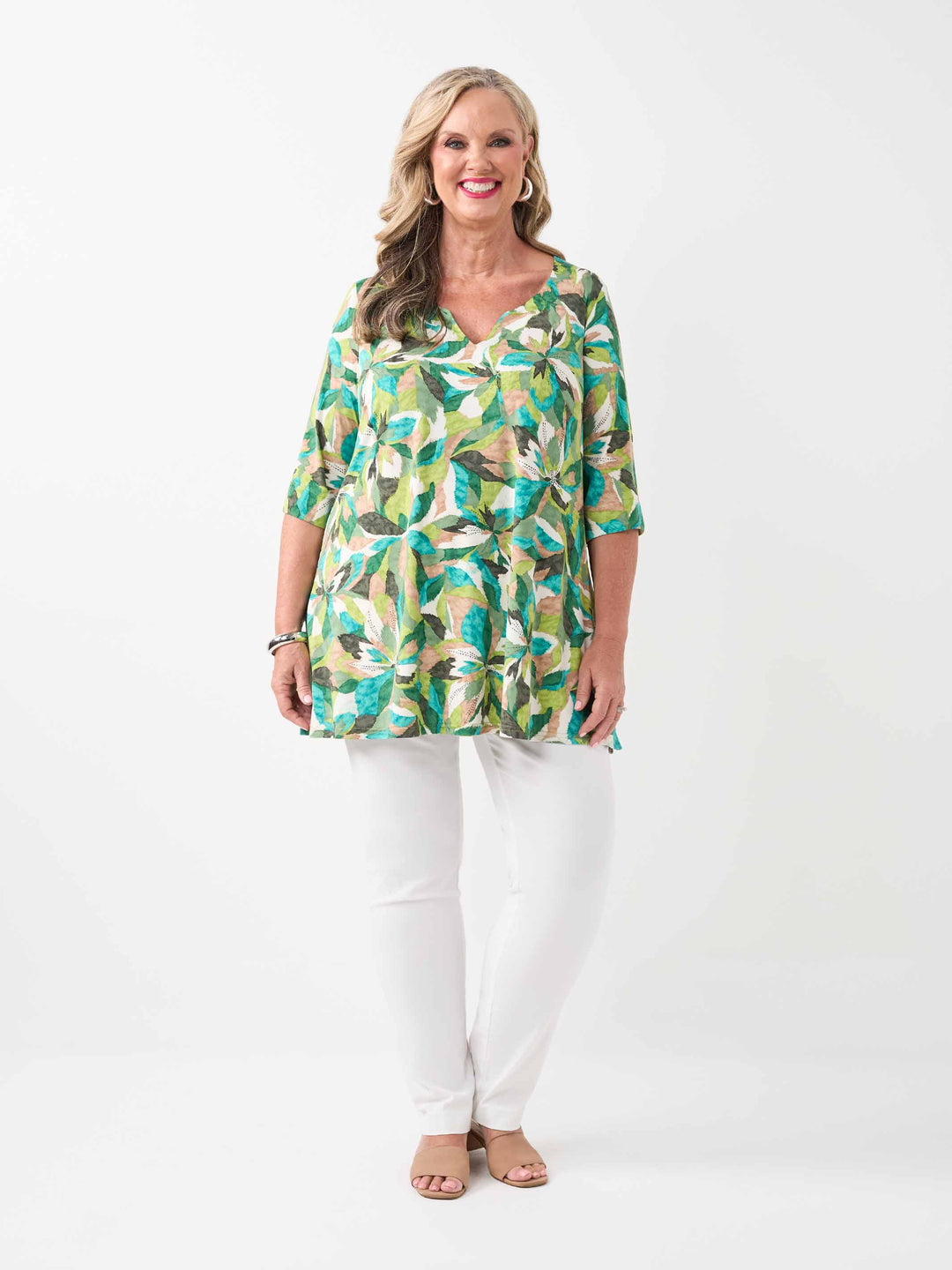 A woman wearing a green tropical floral print tunic top with three-quarter sleeves