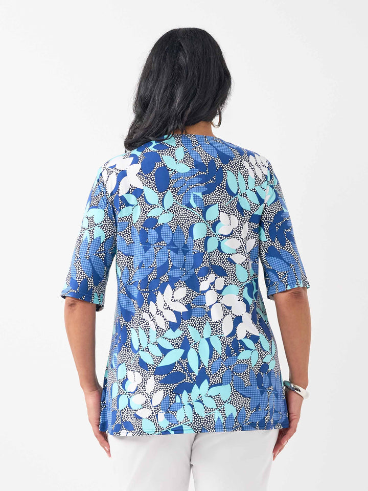 back view of a woman wearing a short-sleeve top in blue shade with textured white fern detail.