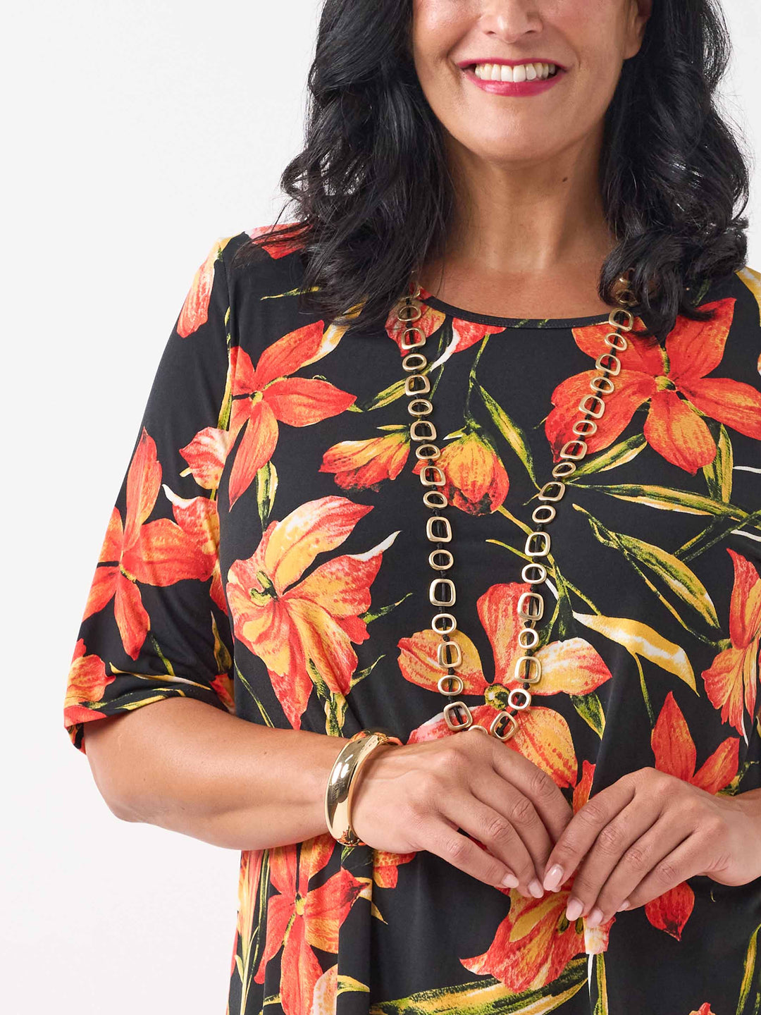 detail view of black short-sleeve top with a vibrant orange and red floral print