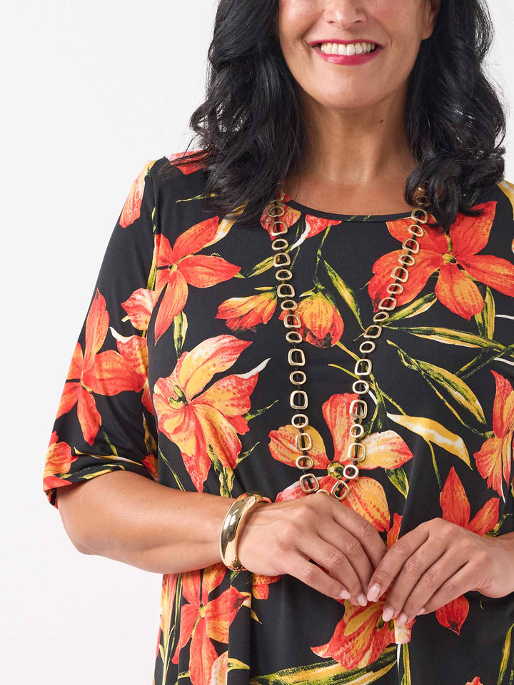 detail view of black short-sleeve top with a vibrant orange and red floral print
