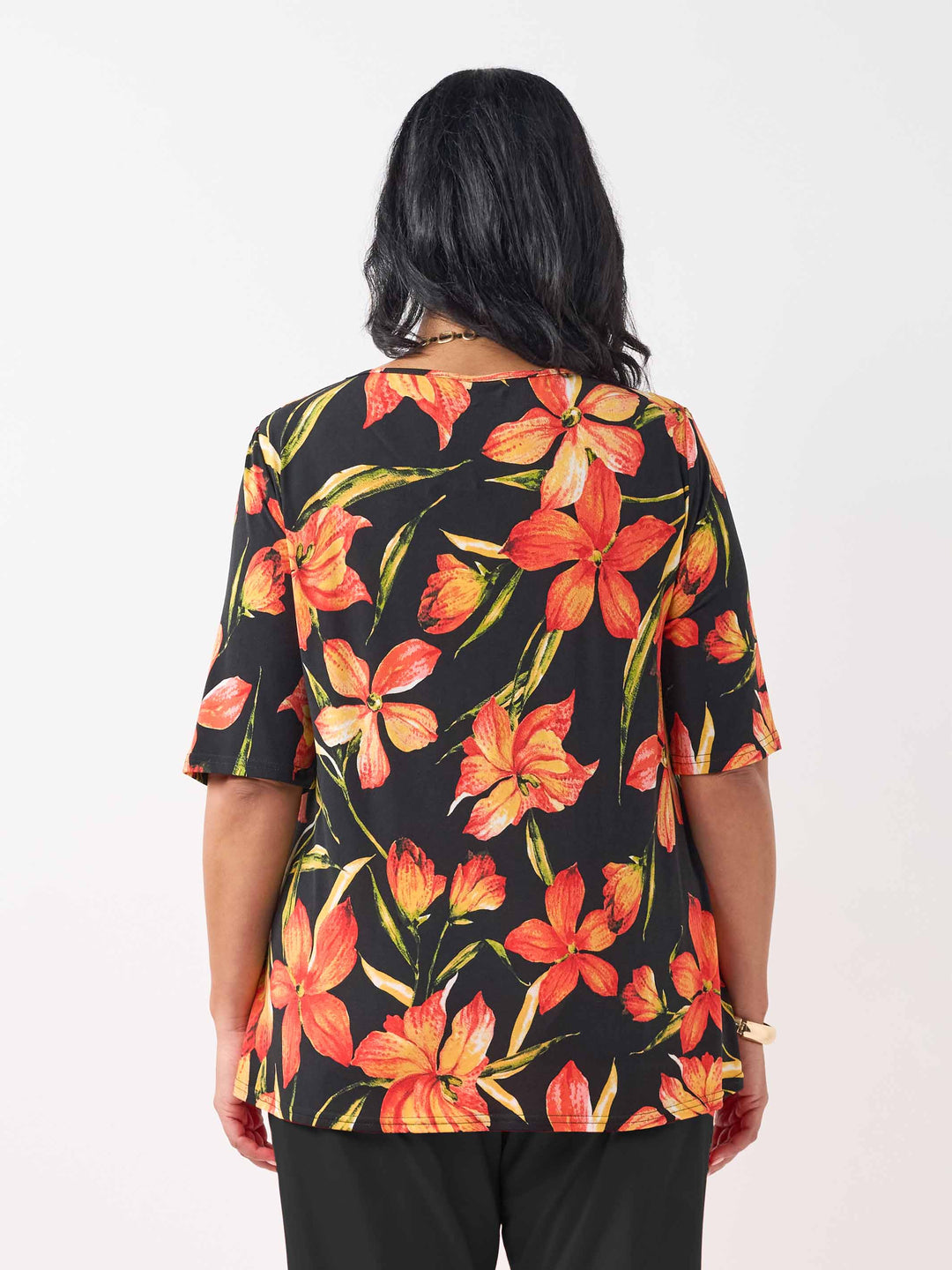 back view of model wearing a black short-sleeve top with a vibrant orange and red floral print
